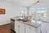 Bright and modern living space featuring a sleek kitchen island, cozy corner sofa, and large windows with abundant natural light.