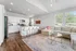 Bright open-concept living space with modern kitchen, sleek breakfast bar, cozy sectional sofa, and large windows offering abundant natural light.