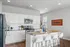 Modern kitchen with white cabinetry, stainless steel appliances, and a sleek granite island with bar seating under recessed lighting.