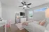 Charming bedroom with elegant fan, plush pink accents, and abundant natural light through large windows.