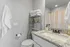 Charming bathroom with modern decor, featuring a granite countertop, elegant faucet, and a neatly organized shelf with fresh towels.