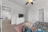 Cozy bedroom featuring vibrant bedding, modern ceiling fan, and sleek white dresser with a mounted TV, offering a tranquil and homely atmosphere.