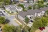 Charming suburban neighborhood aerial view showcasing modern townhomes, tree-lined streets, and ample parking.