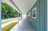 Spacious covered walkway with modern teal siding, nestled in a lush, green neighborhood.
