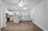 Bright, modern open-concept living area with hardwood floors, ceiling fan, and sleek kitchen featuring stainless steel appliances.
