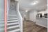 Modern open-concept living space with stylish wooden floors, sleek kitchen, and inviting stairway.