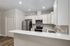 Modern kitchen with sleek white cabinetry, stainless steel appliances, and elegant wood flooring, perfect for culinary enthusiasts.