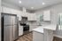 Modern kitchen with sleek stainless steel appliances, white cabinetry, and hardwood floors, featuring a bright and airy atmosphere.