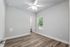 Bright and airy bedroom with elegant wood flooring, large window, and ceiling fan for comfort.