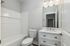Modern bathroom featuring elegant fixtures, white vanity with ample storage, and a sleek bathtub, illuminated by stylish overhead lighting.