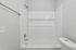 Bright and modern bathroom featuring a sleek bathtub with a tiled wall and a white toilet, offering a serene and clean ambiance.