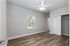 Bright bedroom with elegant wood flooring, ceiling fan, and spacious closet, filled with natural light from a large window.