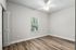 Bright and airy empty room with large window, ceiling fan, and elegant wood flooring, perfect for customization.