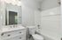 Bright and modern bathroom with elegant fixtures, featuring a spacious bathtub, sleek white vanity, and stylish lighting.