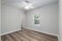 Bright bedroom with sleek wooden floors, ceiling fan, and natural light streaming through a window.