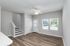 Bright and modern living area with elegant wood flooring, ceiling fan, and natural light from large windows. Convenient stairway access and sleek door design enhance the space.
