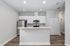 Sleek modern kitchen with stainless steel appliances and elegant white cabinetry, featuring a spacious breakfast bar and rich wood flooring.