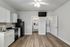 Modern kitchen with sleek white cabinetry, stainless steel appliances, and elegant wood flooring, complemented by a ceiling fan and in-unit laundry for convenience.