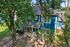 Charming two-story blue house with a welcoming porch, nestled among lush trees in a serene neighborhood.