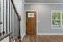 Inviting entryway featuring a warm wooden door, elegant staircase with wrought iron balusters, and bright hardwood flooring.