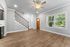 Bright and inviting living area with sleek wooden flooring, stylish ceiling fan, and abundant natural light from large windows.