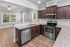 Modern kitchen with sleek stainless steel appliances, rich dark wood cabinets, and elegant granite countertops opening into a bright living area with hardwood floors.