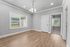 Bright and inviting room with elegant wood flooring, large window, and stylish lighting, offering potential for a cozy living space.