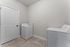 Bright and spacious laundry room featuring modern washer and dryer, sleek tile flooring, and a clean, minimalist design.