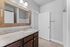 Elegant bathroom with a granite countertop, wooden framed mirror, and ample lighting.