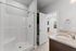 Modern bathroom with elegant granite countertop, spacious shower, and view into a bright living area with hardwood floors.