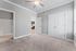Bright and spacious bedroom featuring plush carpeting, elegant ceiling fan, and direct access to a stylish bathroom and modern kitchen.