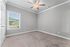 Elegant bedroom with soft gray walls, plush carpet, and natural light streaming through a large window.