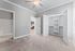 Bright bedroom with plush carpet, spacious closet, and a glimpse of the elegant kitchen, offering modern comfort and style.