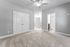 Bright and spacious room with plush carpeting, a ceiling fan, and modern double doors leading to a bathroom and an adjacent room.