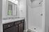 Modern bathroom with elegant granite countertop, sleek vanity, and spacious shower enclosure.