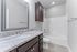 Modern bathroom featuring elegant granite countertops, sleek dark cabinetry, and a pristine bathtub with contemporary fixtures.