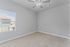 Bright and spacious bedroom with soft carpet, neutral walls, and a stylish ceiling fan, perfect for customization.