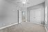 Bright bedroom with plush carpeting, elegant double doors, and ample natural light from large windows.