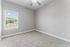 Bright and spacious bedroom with a large window offering scenic views, fresh neutral decor, and plush carpeting.