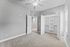 Bright and spacious bedroom featuring an open closet, plush carpeting, and a stylish ceiling fan.