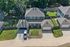 Charming aerial view of a stylish suburban home with a spacious driveway, vibrant green lawn, and privacy fences in a tranquil neighborhood setting.