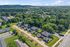 Charming neighborhood aerial view showcasing cozy homes nestled among lush greenery with scenic mountains in the background.