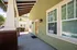 Inviting covered porch with vibrant green exterior, elegant wooden beams, and large windows providing natural light.