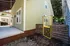 Charming side view of a light green house with a welcoming porch and bright yellow gate, offering cozy outdoor space and modern appeal.