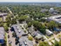 Aerial view of a charming suburban neighborhood with lush trees, modern buildings, and a vibrant, green landscape.