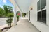 Inviting covered porch of a modern apartment, featuring elegant lighting and a serene street view with lush greenery.