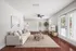 Bright and inviting living room featuring elegant wooden floors, a cozy beige sofa, modern decor, and abundant natural light from large windows and glass doors.