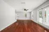 Bright and airy living room with rich wooden floors, large windows, and double French doors opening to a private patio.