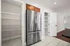 Modern kitchen design featuring a sleek stainless steel refrigerator, ample pantry storage, and elegant tile flooring.