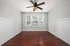Bright and inviting room with rich hardwood floors and a ceiling fan, enhanced by natural light streaming through large windows.